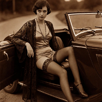 She Always Wins the Race Young woman sits in a vintage convertible with open top, one foot on the road, one inside. She wears a lace peignoir over satin briefs, silk stockings with...