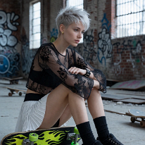 Whispers in the Ruins: Grace Meets Grit on the Warehouse Floor In an abandoned warehouse in Los Angeles, a young woman with a short pixie cut sits on the concrete floor. Her black tulle top with lace trim and the bandeau...